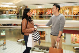 Woman in Mall carrying shopping bags talking to man