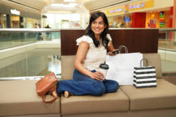 woman sitting on couch with shopping bags in mall